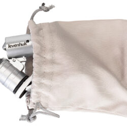 74108_levenhuk-pocket-microscope-zeno-cash-zc4_02 Srebrny mikroskop kieszonkowy Levenhuk wystający z beżowego woreczka materiałowego.