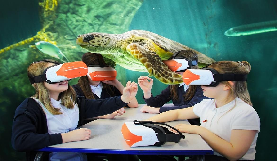 Uczniowie w goglach VR wirtualnie obserwujący żółwia morskiego w klasie.