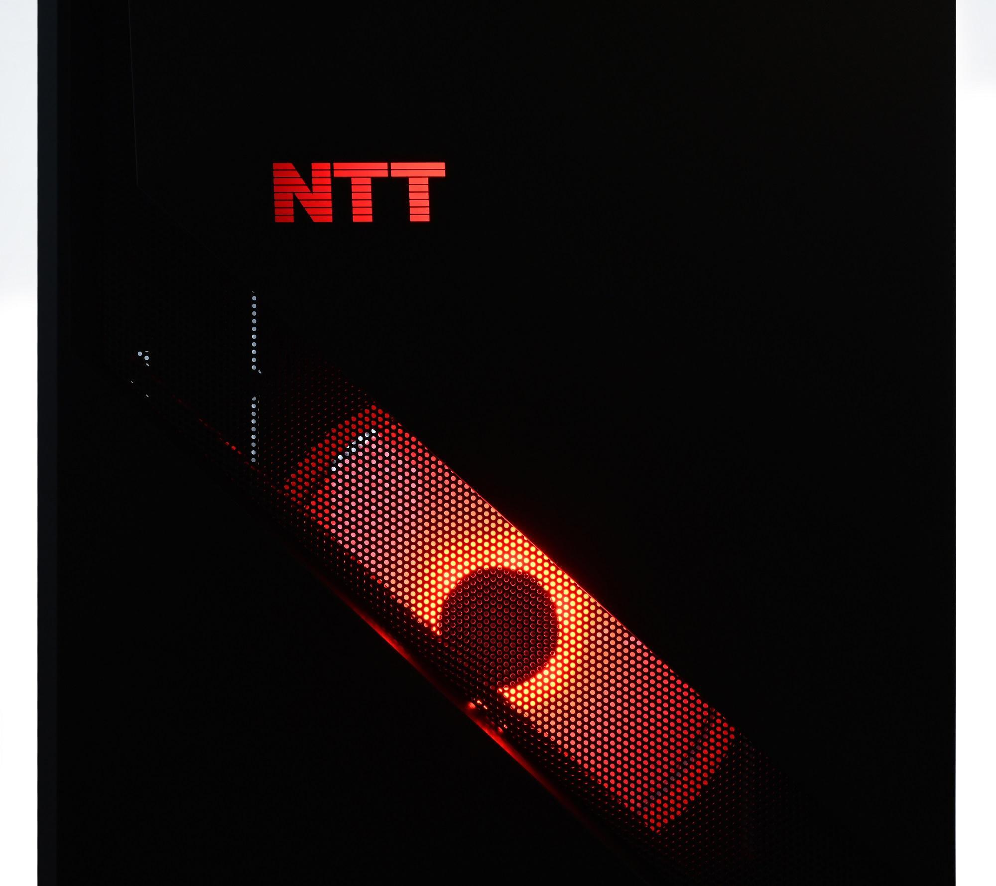 Logo NTT na czarnej obudowie komputera z podświetlanym na czerwono panelem przednim.